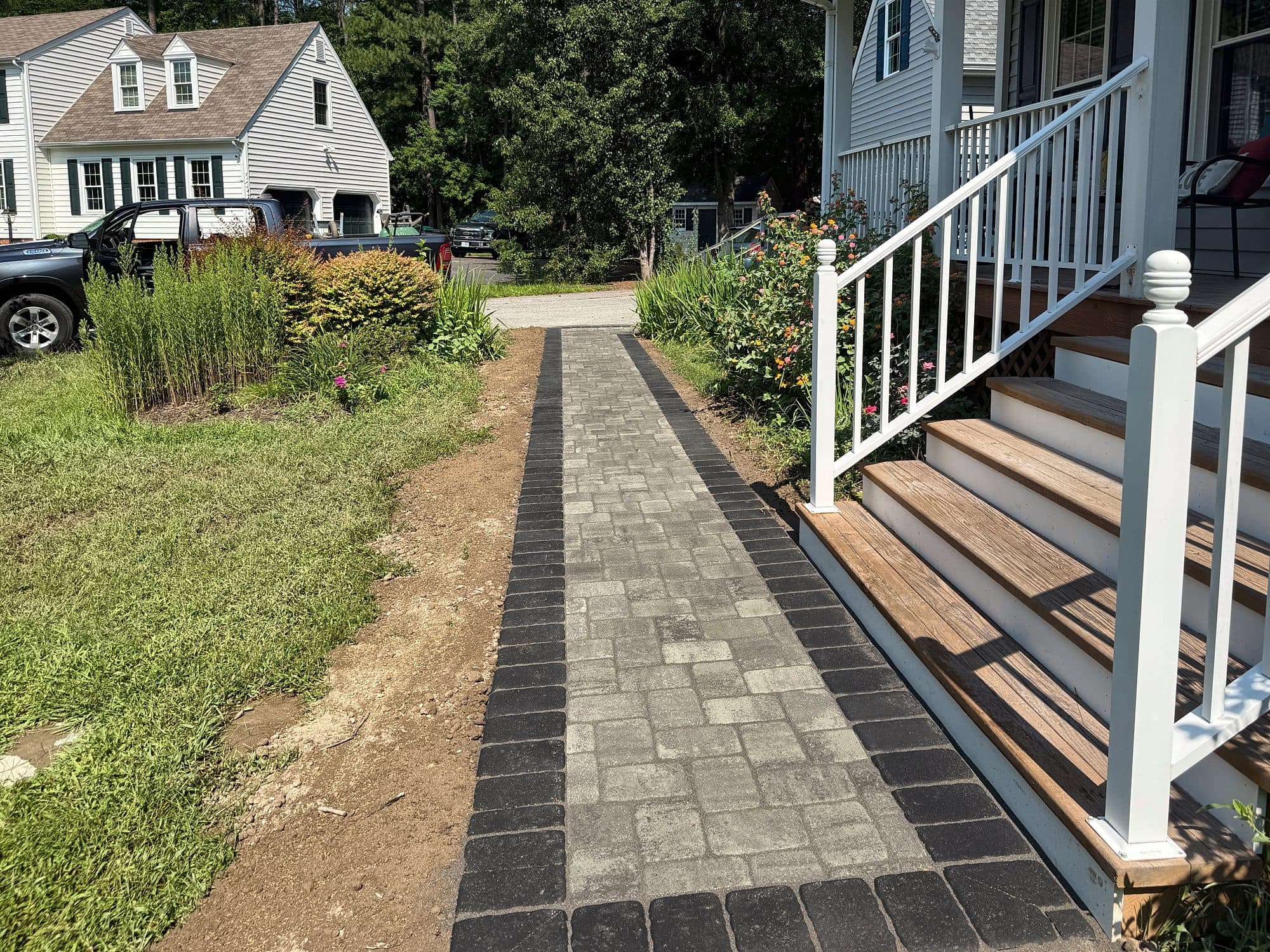 Paver walkway with a charcoal border running from front porch steps toward the driveway.