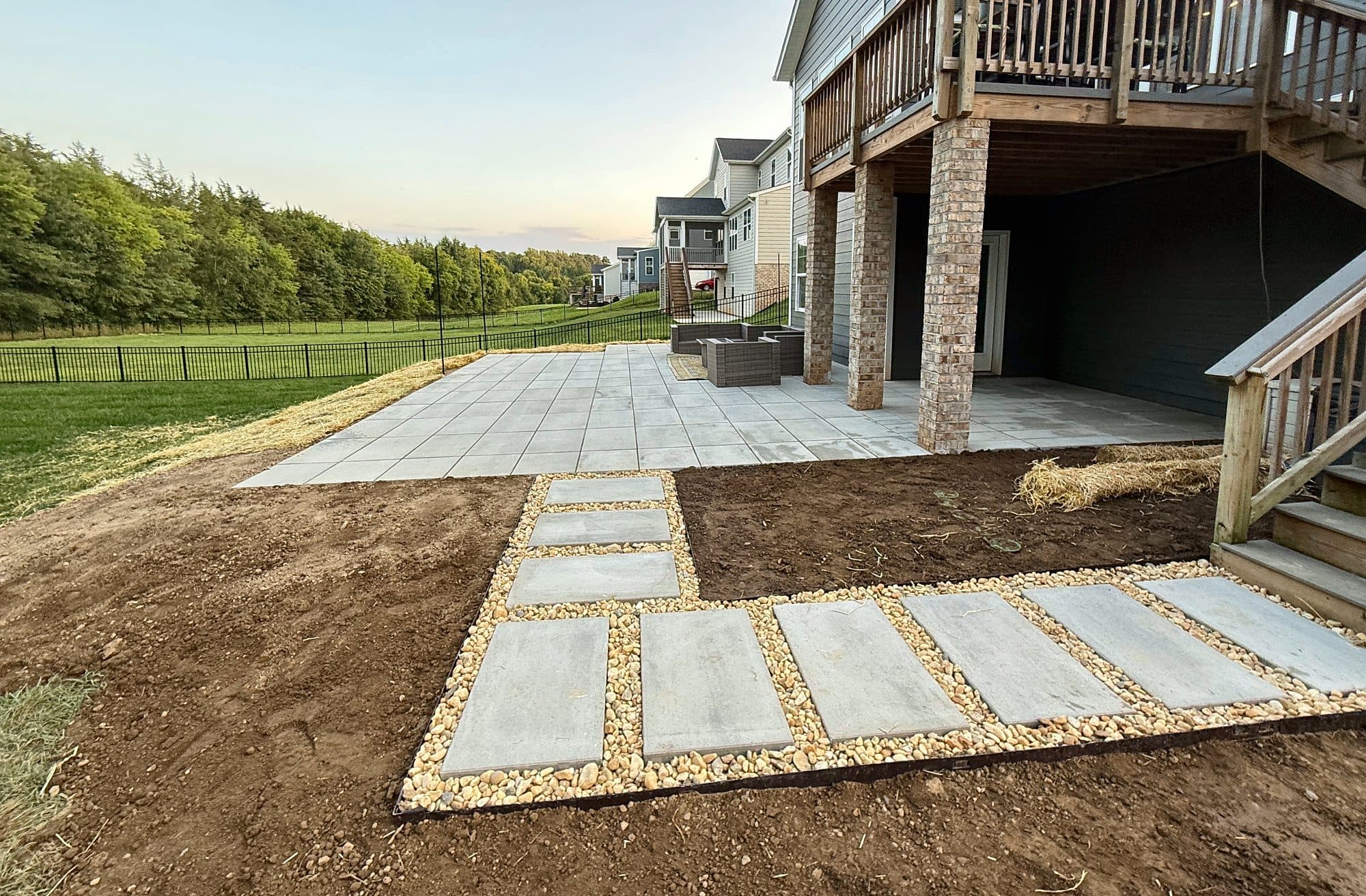 Stepping slabs set in river rock leading from deck stairs to a large-format slab patio.