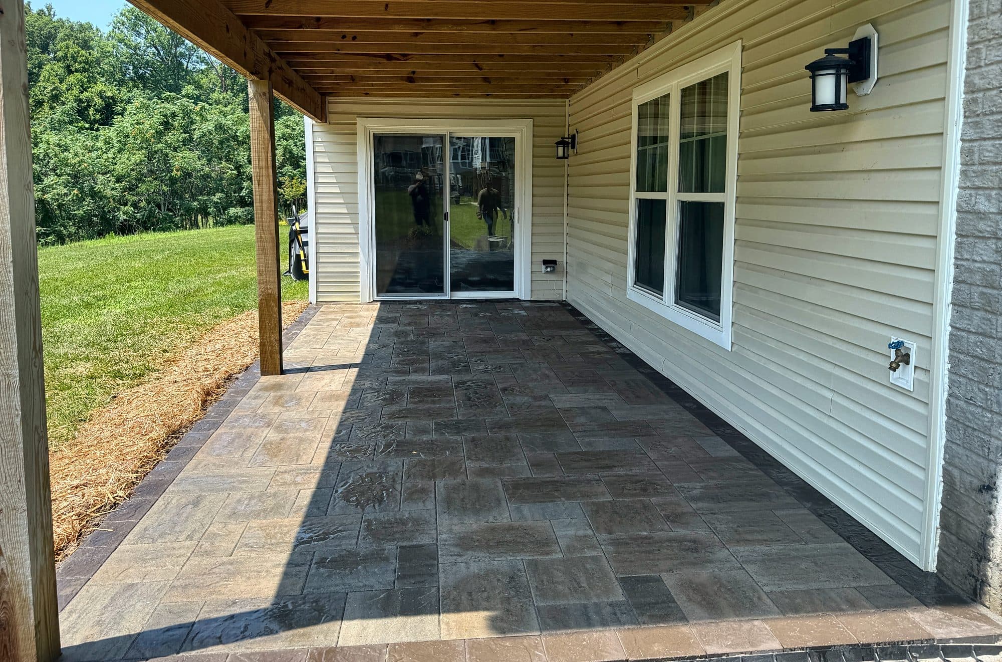 Paver patio with a contrasting border built beneath a raised deck at a walk-out door.